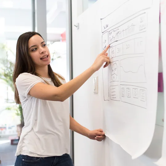 A designer sketching a website wireframe on a whiteboard