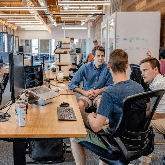 A team talking through a project at their desks in an open-plan office